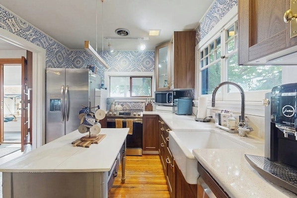 A kitchen with a central island, stainless steel appliances, and a coffee machine.