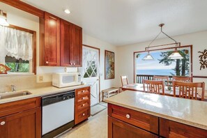 A kitchen with wooden cabinets, a microwave, and a view of the ocean. - Waterfront Cabin with Hot Tub and Mountain Views in Eastsound (Eastsound)
