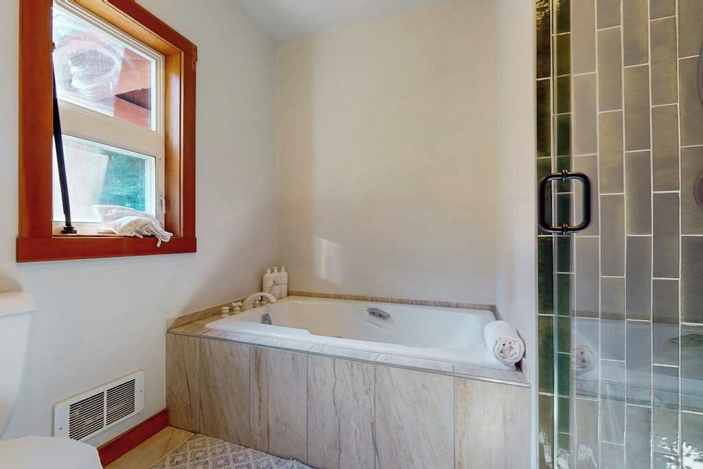 Un baño con bañera, ventana y zona de ducha.