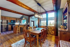A spacious kitchen with wooden beams, a dining area with a large table and chairs, and a stone accent wall.