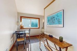 A dining area with a table and chairs, a window, and a wall-mounted map. - Beautiful Secluded Cabin with Stunning Bay Views and Private Deck (Eastsound)