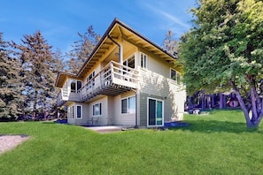 A two-story house with a balcony, a covered porch, and a well-maintained lawn.