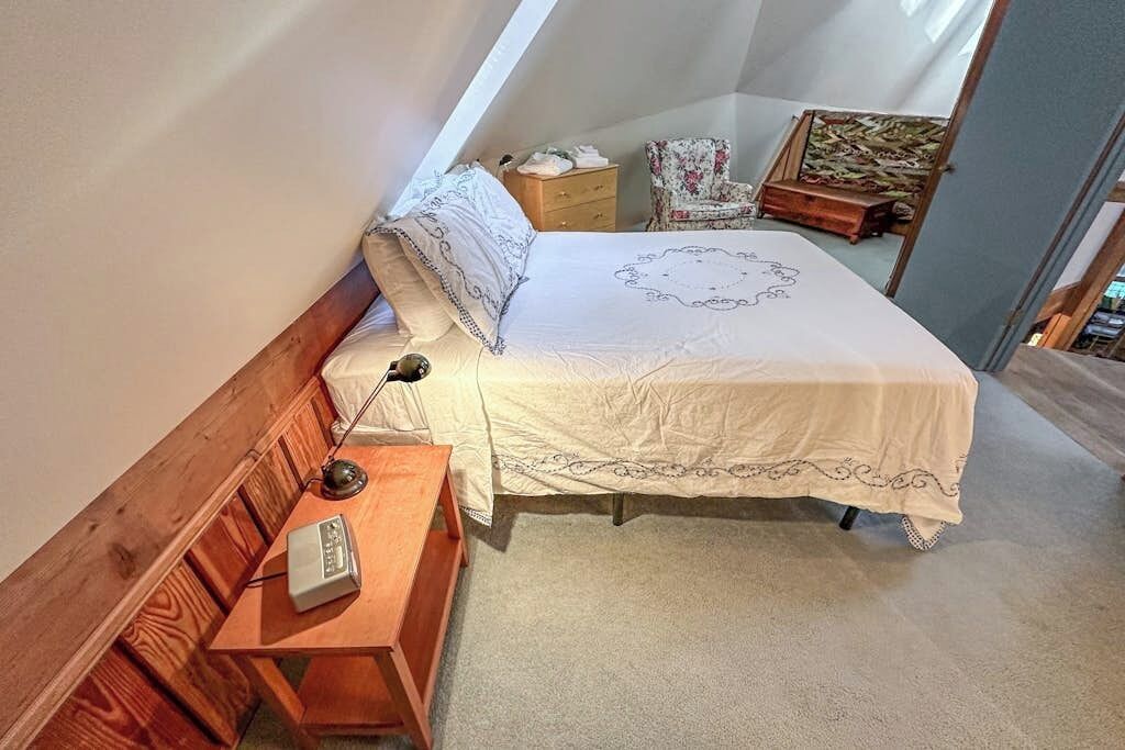 A small, cozy bedroom with a single bed, a nightstand, a chair, and a dresser.