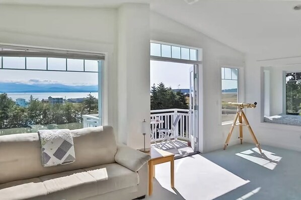 A spacious room with a large window, a white balcony, and a telescope.