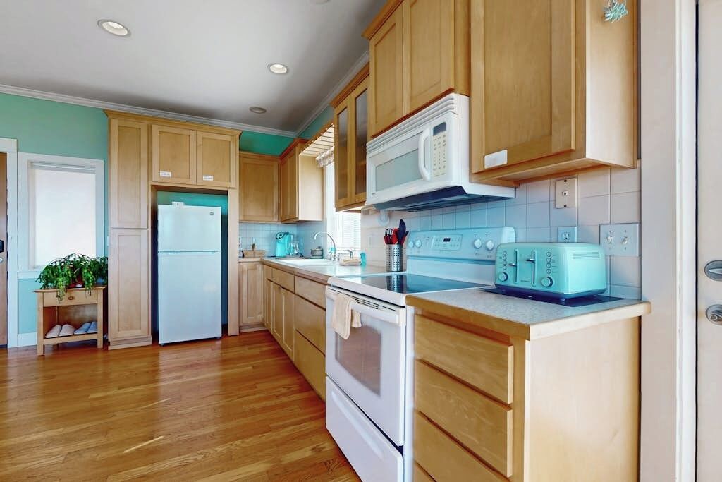 Una cocina con armarios de madera, un refrigerador blanco, un microondas, una estufa y un tostador.