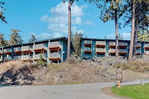 Un edificio a più piani con balconi, un'area di parcheggio e una segnaletica indicativa.