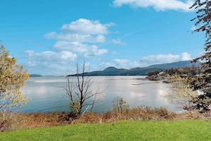 Un lago con cielo sereno, circondato da alberi e colline.