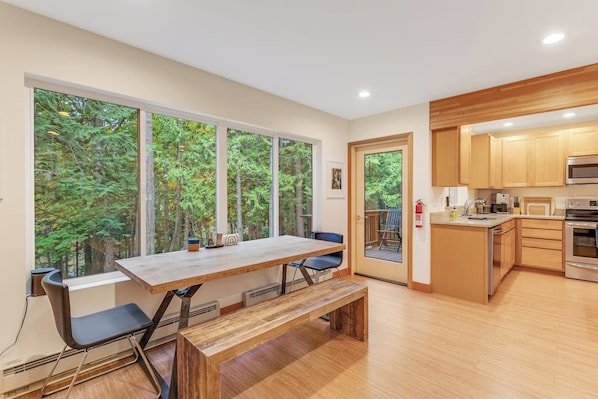 A modern kitchen with wooden cabinets, a large island, and a view of the outdoors.