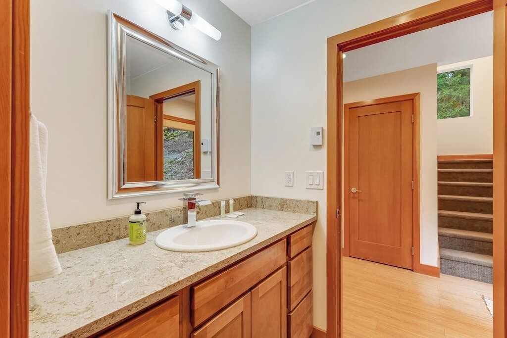 Une salle de bain avec un lavabo, un miroir et des meubles en bois.