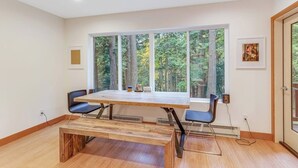 Una habitación con un ventanal grande, una mesa de madera, dos sillas y un banco.