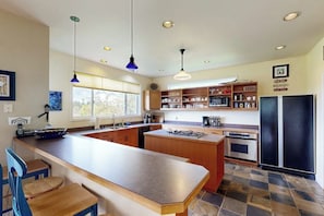 Een moderne keuken met een centraal kookeiland, houten kastjes en een zwarte koelkast.