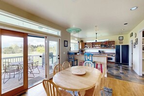 A spacious kitchen with a dining area, large windows, and a deck.
