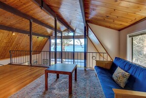A room with a wooden ceiling, a blue sofa, a wooden table, and a view of the outdoors.
