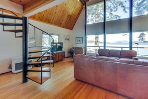A modern interior with a wooden staircase, a large window with a view, and a plush sofa.