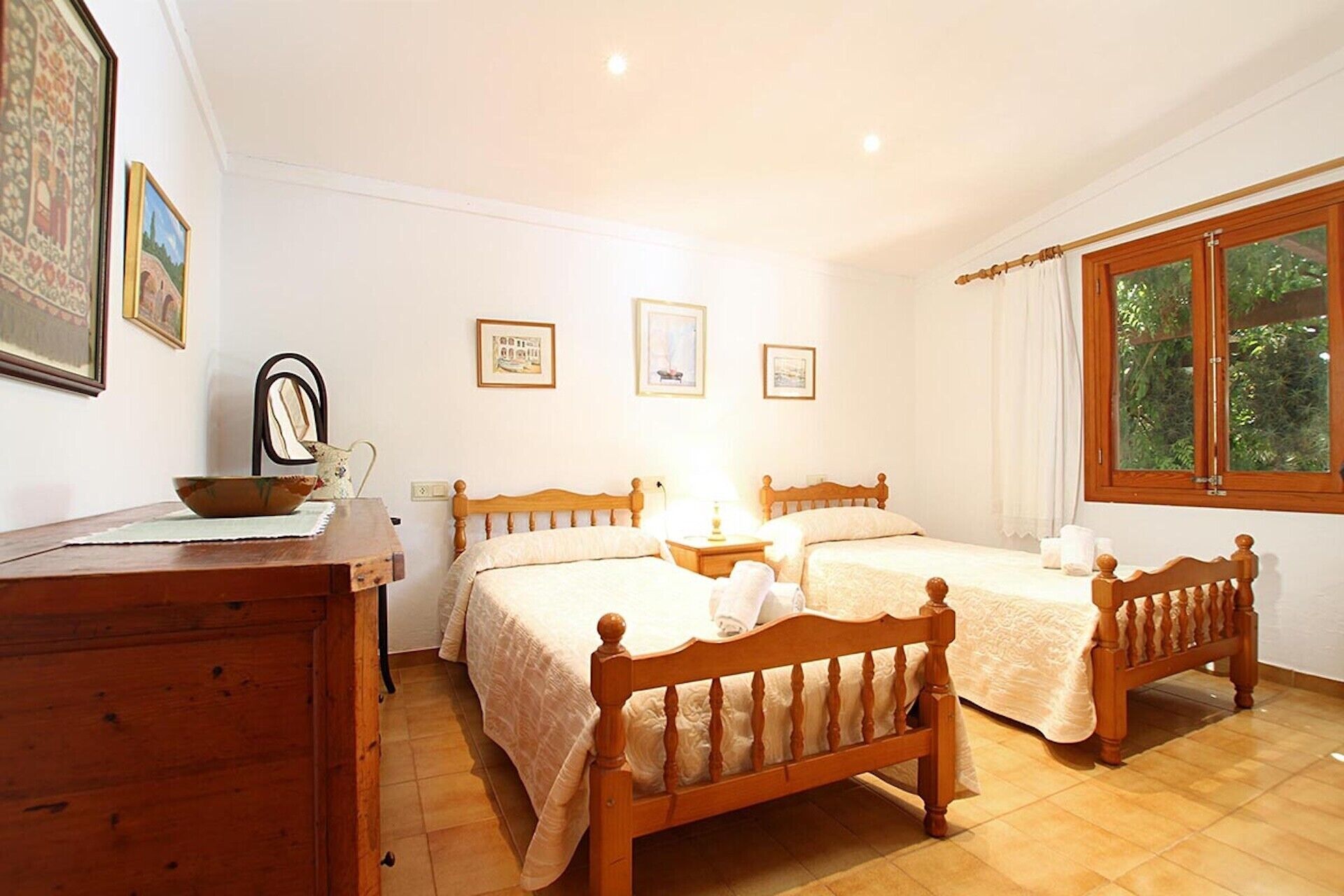 A bedroom with two wooden beds, a bedside table, a chair, and a window with curtains.