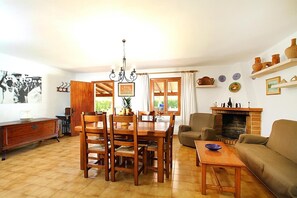 Uma sala de jantar com mesa e cadeiras de madeira, um sofá, lareira e vista para o exterior.