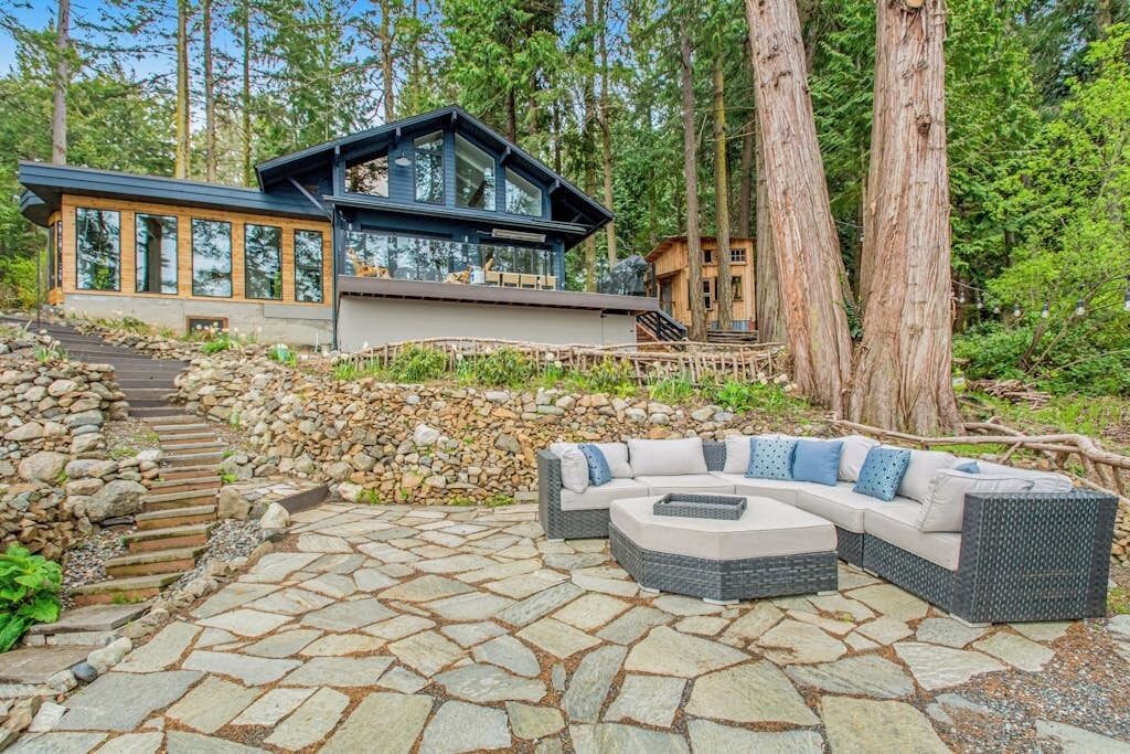 Une maison moderne dotée d’une terrasse en pierre et de mobilier d’extérieur.