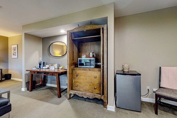 A compact living space with a wooden cabinet, a small refrigerator, and a dining table.