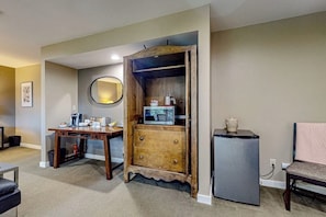 Un espacio habitable compacto con un armario de madera, un refrigerador pequeño y una mesa de comedor.