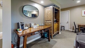 Quarto com uma mesa de madeira, cafeteira, torradeira e espelho na parede.