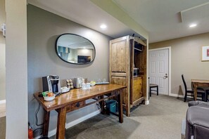Una habitación con una mesa de madera, una cafetera, un tostador y un espejo en la pared.