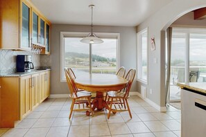A kitchen with a dining table, chairs, and a view through the window. - Waterfront Home with Private Sauna and Kayaks in Oak Harbor (Oak Harbor)
