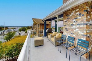A balcony with outdoor seating, a view of a marina, and a brick wall. - Waterfront Home with Private Sauna and Kayaks in Oak Harbor (Oak Harbor)