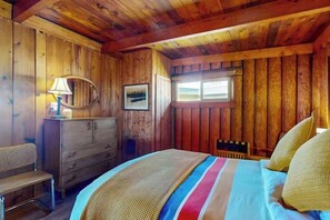 Ein Zimmer in einer Holzhütte mit einem Bett, einem Schminktisch, einem Stuhl und einem Fenster.