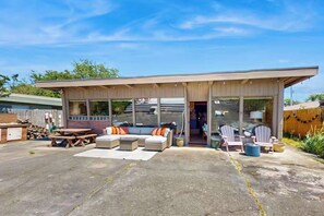 Ein überdachter Außenbereich mit Picknicktisch, Sofas und Sesseln.