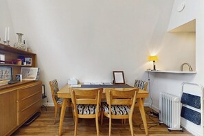 A dining area with a table and chairs, a radiator, and a shelf with decorative items. - Cozy Island Retreat near Beaches, Trails, and Langley! (Langley)