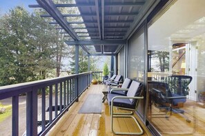 A covered outdoor area with a wooden deck, metal railings, and several chairs. - Cozy Island Retreat near Beaches, Trails, and Langley! (Langley)