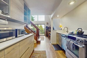 A modern kitchen with built-in appliances, a wooden staircase, and a view to the outdoors. - Cozy Island Retreat near Beaches, Trails, and Langley! (Langley)