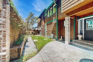 A residential property with a brick wall, wooden siding, a paved driveway, and a small lawn area. - Relaxing Waterfront Studio Cottage with Private Beach Access (Clinton)