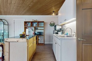 A compact kitchen with wooden cabinets, a built-in microwave, and a sink. - Relaxing Waterfront Studio Cottage with Private Beach Access (Clinton)