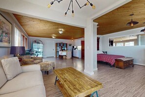 Un vaste espace de vie doté d’un plafond en bois, d’un canapé, d’une table basse et d’un lit recouvert d’une couverture rouge.