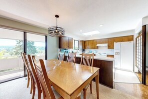 A modern kitchen with wooden cabinets, a dining table with chairs, and a large window offering a view. - Hawk Lane Hideaway: Spacious 4 Bedroom Waterfront Retreat with Hot Tub (Greenbank)