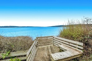 A wooden bench overlooking a body of water with a clear sky. - Eastside Beachside Greenbank Getaway (Greenbank)