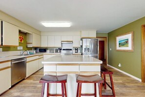 A modern kitchen with a central island, bar stools, and stainless steel appliances. - Eastside Beachside Greenbank Getaway (Greenbank)