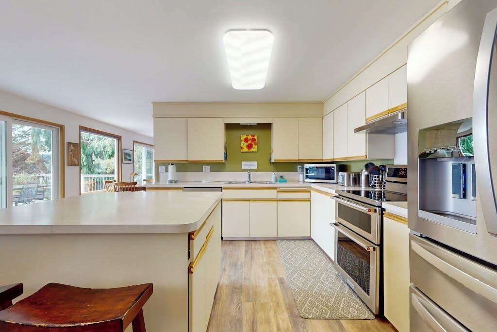 A modern kitchen with a central island, built-in appliances, and a view to the outdoors.