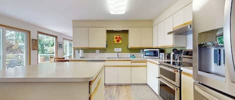 A modern kitchen with a central island, built-in appliances, and a view to the outdoors.