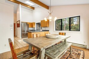 Eine moderne Küche mit Holzschränken, einem Edelstahlkühlschrank und einem Essbereich mit Holztisch und Bänken.