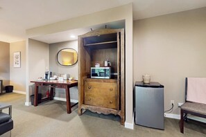 A compact living space with a kitchenette, a wooden cabinet, a microwave, a refrigerator, a round mirror, and a chair. - Stunning 3 Ocean View Condos near Moran State Park with Balconies (Eastsound)