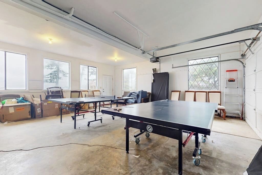 A spacious indoor area with a ping pong table, chairs, and a large window.