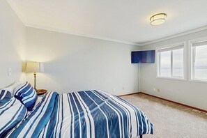 Ein Schlafzimmer mit einem Bett, einem an der Wand befestigten Fernseher und einem Fenster.