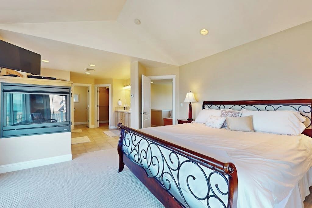A hotel room with a large bed, a television, and a bathroom visible through an open door.