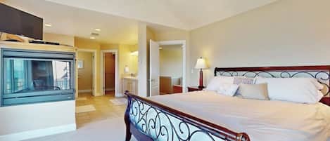 Une chambre d’hôtel avec un grand lit, une télévision et une salle de bain visible à travers une porte ouverte.