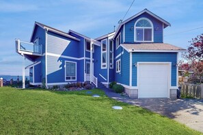 Ein zweigeschossiges Haus mit Garage, Balkon und einem gepflegten Rasen.