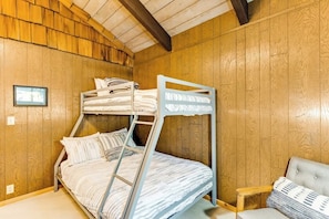 A bunk bed room with wooden walls and a small table.