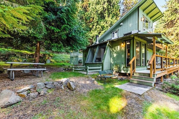 A cabin with a porch, a picnic table, and a stone wall. - Fantastic Waterfront Retreat in Eastsound with Expansive Deck and Stylish Interior - Dog Friendly (Eastsound)
