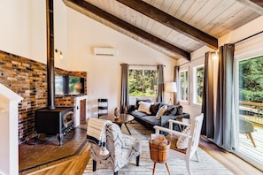 Una sala de estar acogedora con chimenea, asientos cómodos y un amplio ventanal con vistas al exterior.